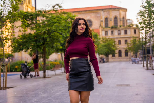 A brunette woman with a leather skirt next to a church visiting the city, lifestyle - Foto, imagen