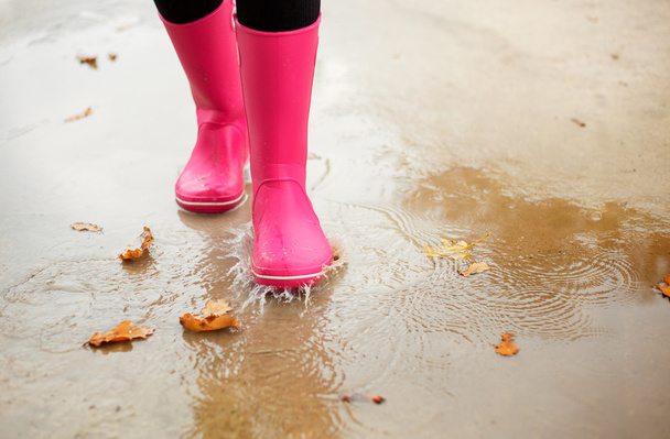 Mujer con botas de goma rosa caminando a través del charco en otoño
 - Foto, Imagen