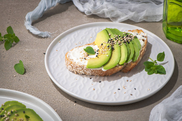 Healthy toast with avocado cream cheese and wheat bread on a plate. Delicious snacks and avocado sandwiches. Food composition, tasty Italian meal. - Photo, image