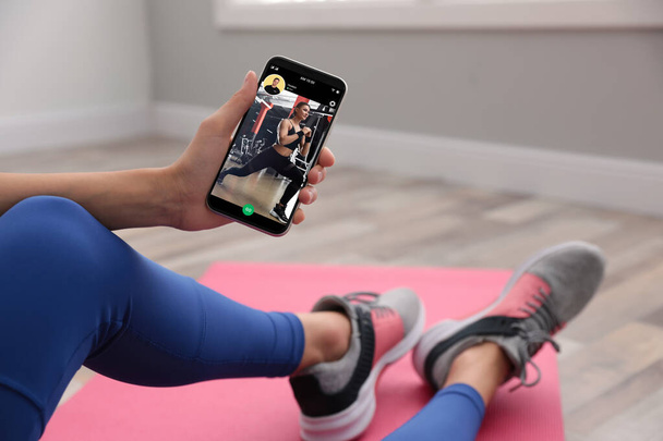 Woman having workout with personal trainer via smartphone at home, closeup - Foto, Imagem