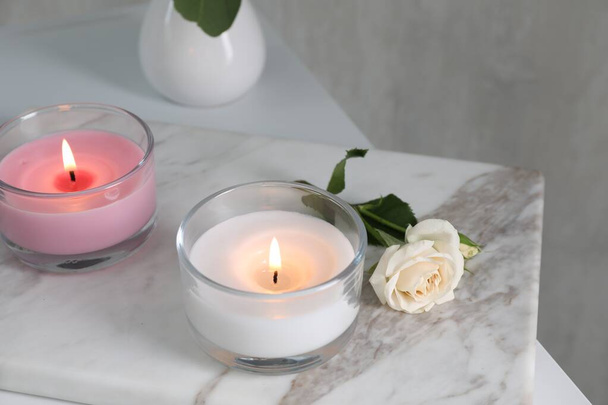 Burning candles and beautiful rose on white marble board - Photo, Image