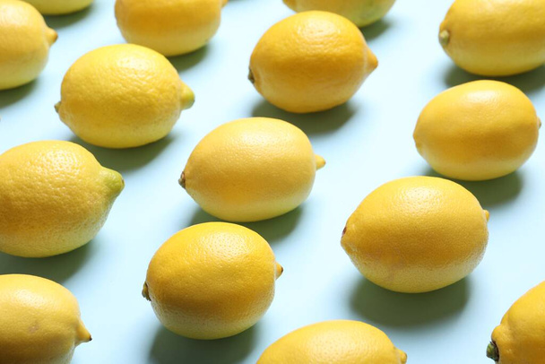Many fresh ripe lemons on light blue background - Фото, изображение