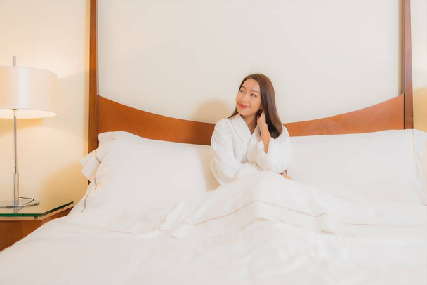 Πορτρέτο όμορφη νεαρή ασιατική γυναίκα χαμόγελο χαλαρώστε αναψυχής στο κρεβάτι στο εσωτερικό υπνοδωμάτιο - Φωτογραφία, εικόνα