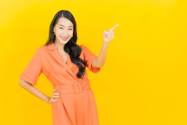 Retrato hermosa joven mujer asiática sonrisa con acción sobre fondo de color amarillo - Foto, Imagen