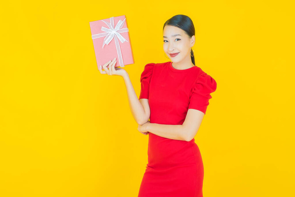 Portrait beautiful young asian woman smile with red gift box on color background - Foto, Imagen