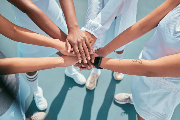 On three... High angle shot of an unrecognisable group of women huddled together with their hands in the middle during tennis practise - 写真・画像