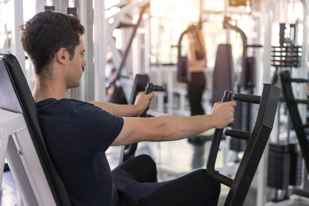 Pohledný muž snižuje hmotnost fitness stroje a cvičení ve fitness tělocvičně - Fotografie, Obrázek