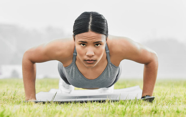 Feel the burn. Full length portrait of an attractive young female athlete doing pushups while exercising outside - Foto, Imagem