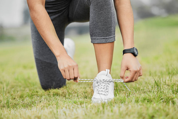 Halten Sie es eng. eine nicht wiedererkennbare junge Sportlerin, die ihre Schnürsenkel bindet, während sie draußen trainiert - Foto, Bild