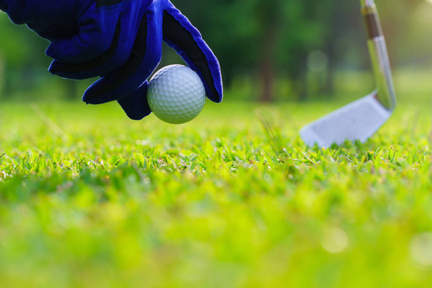 Hand holt einen Golfball vom Fairway auf dem Golfplatz. - Foto, Bild