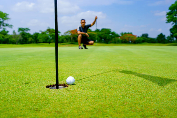Golfer putt golfbal in het gat op de groene golfbaan. - Foto, afbeelding