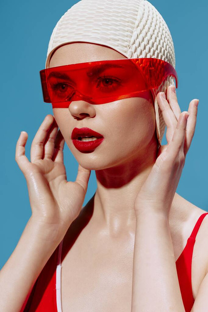 Um olhar para o futuro. NFT. Uma menina do futuro em óculos vermelhos olha para a frente toca um boné de natação. Foto de alta qualidade - Foto, Imagem