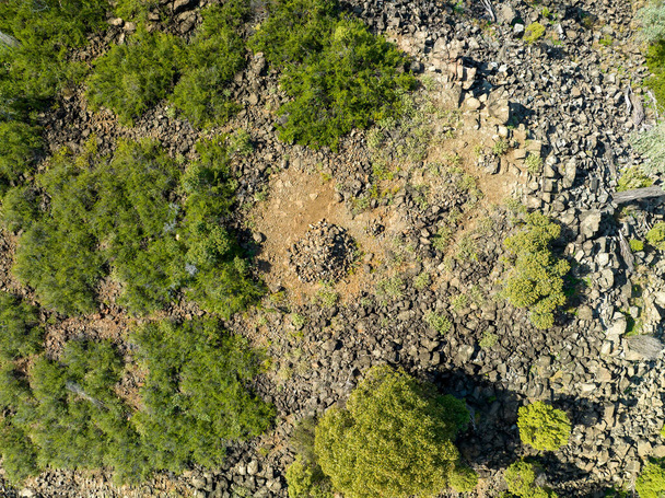 Drone aerial down onto a pile of rocks on top of a stoney mountain amongst bushland. - Photo, image