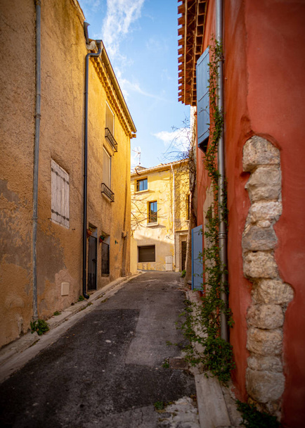 Old street of the village of Gruissan, Southern France, with beige and pink colored walls as well as blue shutters, taken on a sunny winter late afternoon with no people - 写真・画像