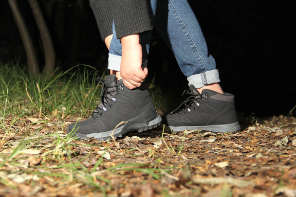 Legs of a person with black hiking boots doing dangerous, adventurous and risky night walk in the forest - Foto, Imagem