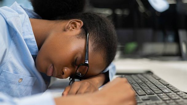 Африканская молодая женщина спит за рабочим столом - Фото, изображение