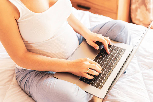Pregnancy digital laptop. Pregnant woman holding digital computer. Mobile pregnancy online maternity notebook application. Concept of pregnancy, maternity, expectation for baby birth - Fotó, kép