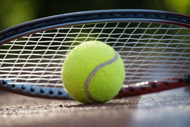 Close-up tennis raket over gele tennisbal op harde banen oppervlak in lage hoek uitzicht - Foto, afbeelding
