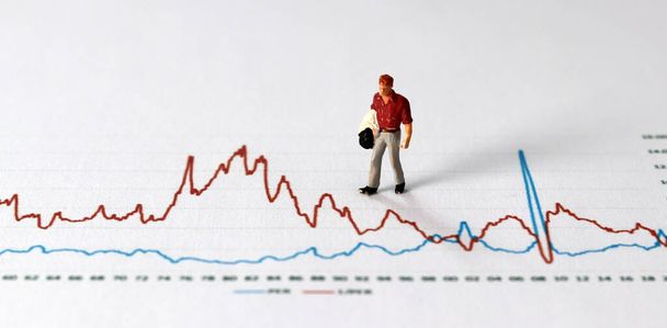 Business concept with graphs and miniature people. A miniature man on the graph. - Foto, Imagem