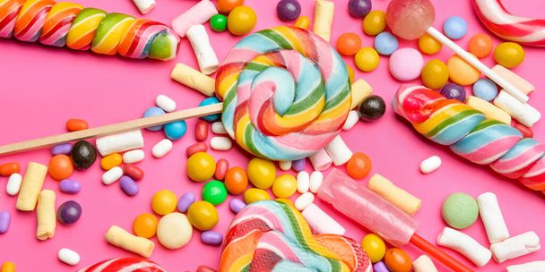 Different tasty candies on pink background - Фото, изображение