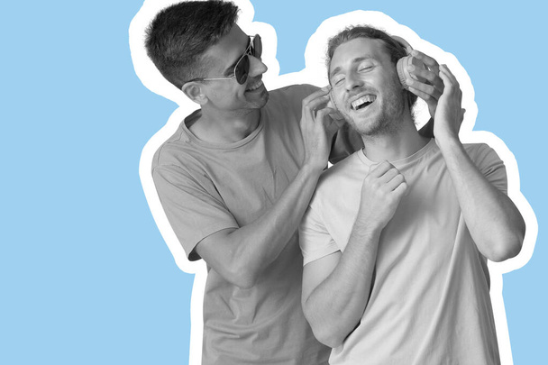 Happy gay couple listening to music on blue background - 写真・画像