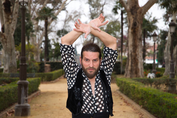 handsome middle-aged man dancing flamenco with long hair and beard was dancing in a park doing different postures with a lot of passion. Concept of flamenco, dance, dance, culture, tourism and art. - Photo, Image