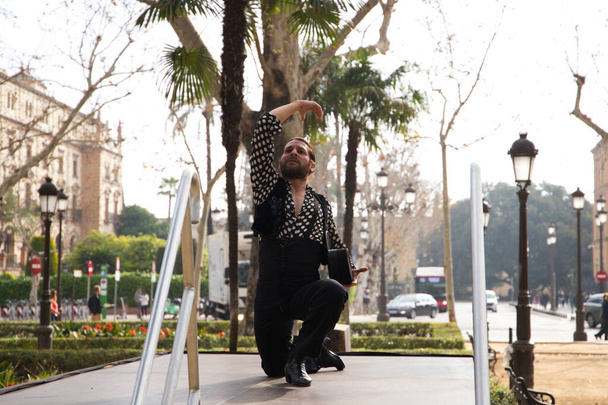 gypsy man with long hair dancing flamenco on an open air stage in a park in seville and he is doing different postures with a lot of passion. Flamenco dance concept cultural heritage of humanity. - Photo, Image