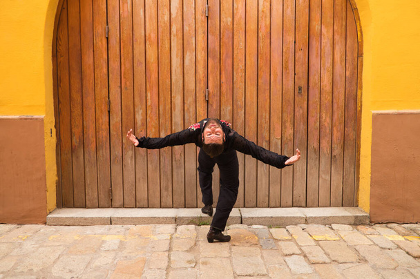 homem dançando flamenco com camisa preta e rosas vermelhas, em um fundo de uma porta de madeira, fazendo posturas diferentes ao dançar. Flamenco dança conceito patrimônio cultural da humanidade. Sinta de paixão. - Foto, Imagem