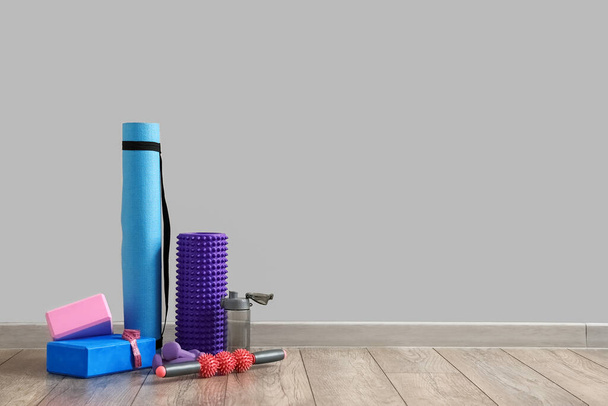 Sports equipment with foam roller and bottle near grey wall - Фото, изображение