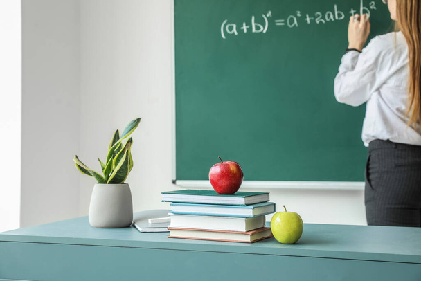Apples with school books and houseplant on table near chalkboard - Photo, image