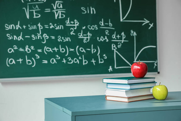 Apples with school books on table near chalkboard - Foto, Bild