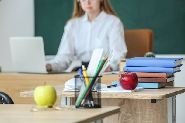 Roter Apfel mit Schulbüchern auf dem Tisch im Klassenzimmer - Foto, Bild