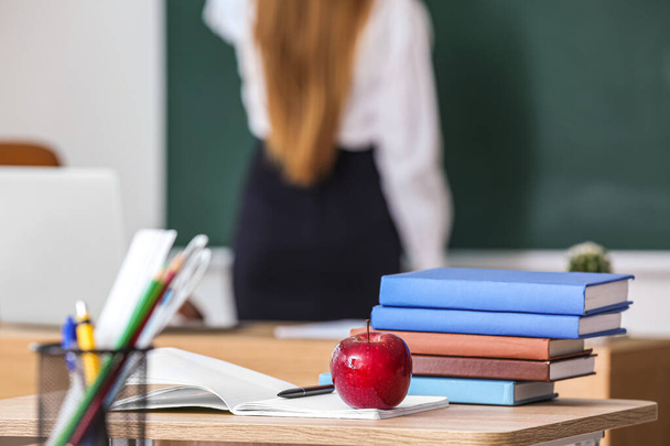 Roter Apfel mit Schulbüchern auf dem Tisch im Klassenzimmer - Foto, Bild