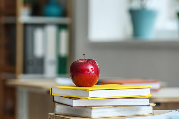 Red apple with school books on table in classroom - Photo, image
