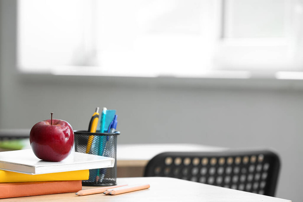 Apple with books, pen cup and school stationery on table in classroom - Φωτογραφία, εικόνα