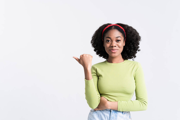 Young black woman smiling and pointing finger aside isolated over white background - Photo, image