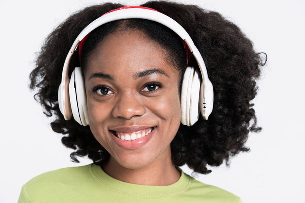 Young black woman smiling while listening music with headphones isolated over white background - Valokuva, kuva