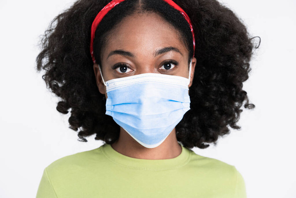 Young black woman wearing in face mask looking at camera isolated over white background - Foto, afbeelding