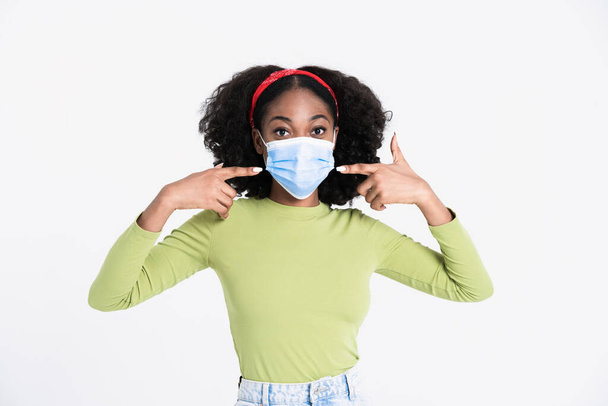 Young black woman pointing fingers at her face mask isolated over white background - Foto, Imagem