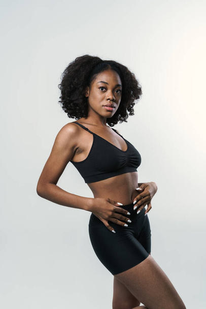 Young black woman in sportswear posing and looking at camera isolated over white background - Foto, Bild