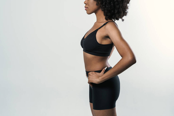 Young black woman in sportswear posing and looking aside isolated over white background - Foto, afbeelding