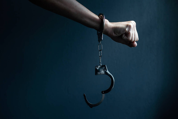male hands in handcuffs black background. - 写真・画像