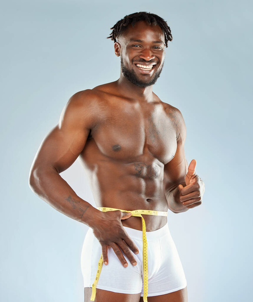 Ive made great progress. Studio shot of an athletic young man measuring his waist - Photo, image