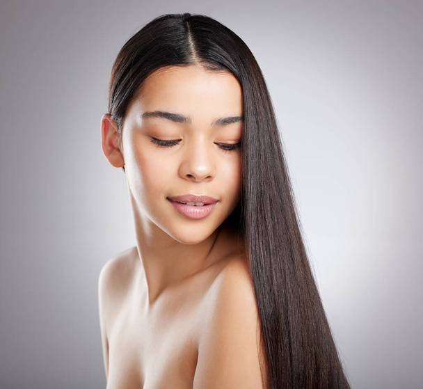 The haircare game is strong with this one. Studio shot of an attractive young woman posing against a grey background - 写真・画像