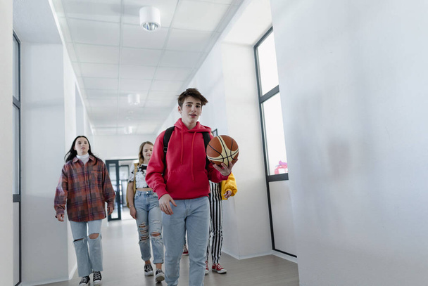 Молодые школьники прогуливаются по коридору в школе, возвращаясь к школьной концепции. - Фото, изображение