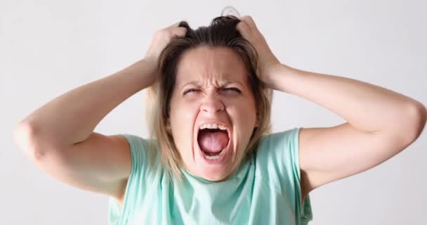 Nuori nainen huutaa ja repii hiuksiaan valkoisella taustalla 4k elokuva. Reaktio suruun huuto käsite - Materiaali, video