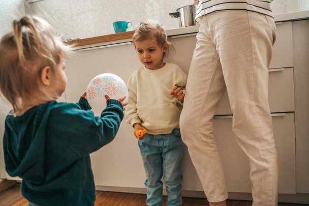 Little girl and her cute sister playing with a balloon while their parent cooking breakfast - Valokuva, kuva