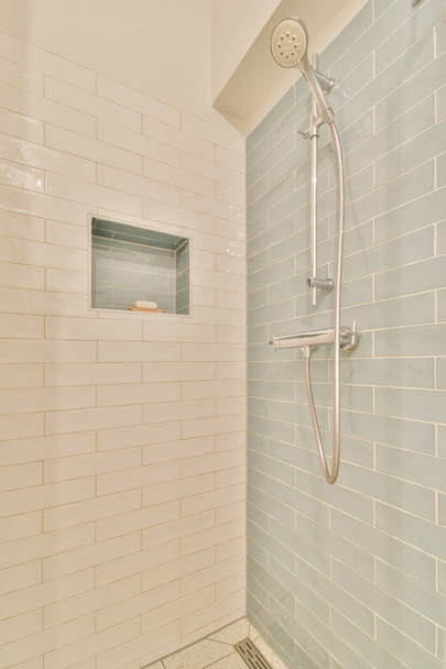 Shower faucets attached to tiled wall near glass partition and ornamental curtail in washroom at home - Photo, Image