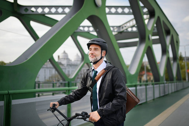 Um viajante de negócios a caminho do trabalho, andar de bicicleta sobre ponte, conceito de estilo de vida sustentável. - Foto, Imagem