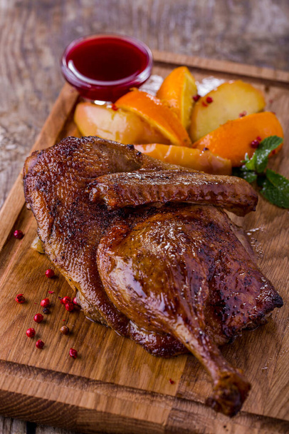Grilled duck carcass in sauce with mint, orange and potatoes on a wooden board. Vertical orientation - Photo, image